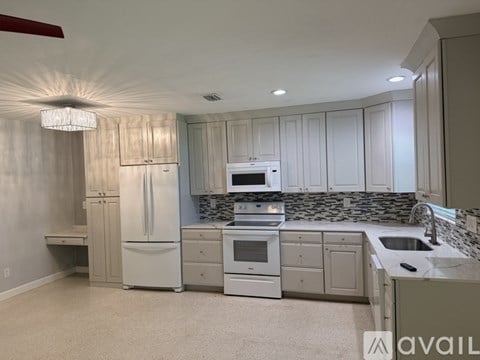 A kitchen with white appliances and a marble countertop.