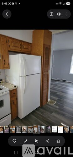 A white refrigerator is in a kitchen with wooden cabinets.