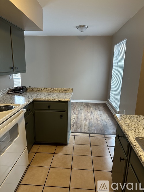 A kitchen with a white stove top oven and a granite counter top.
