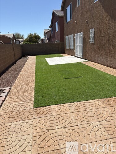 A backyard with a lawn and a brick patterned walkway.