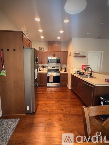 A kitchen with wooden floors and a refrigerator with a green magnet on it.