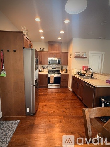 A kitchen with wooden floors and a refrigerator with a green magnet on it.