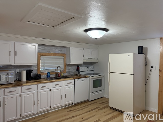 A kitchen with white cabinets and appliances.