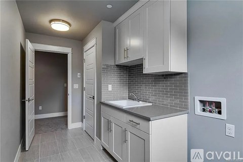 A kitchen with white cabinets and a grey backsplash.