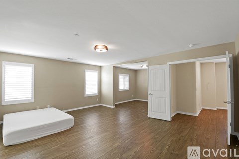 A bedroom with a bed, a window, and a wooden floor.