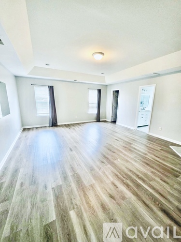 A spacious room with wooden flooring and white walls.