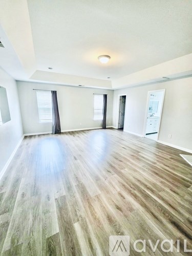 A spacious room with wooden flooring and white walls.