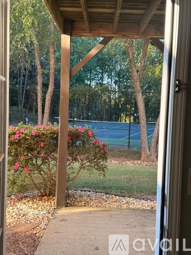 A wooden pergola with a view of a fenced backyard and trees.