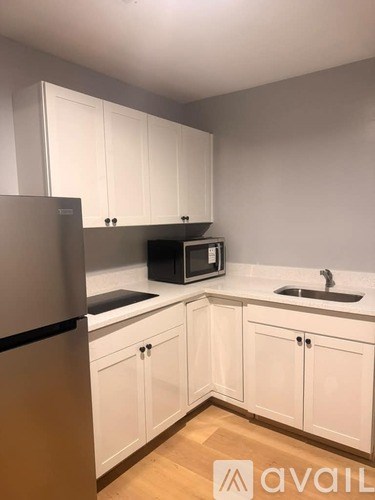 A kitchen with white cabinets and a stainless steel refrigerator.