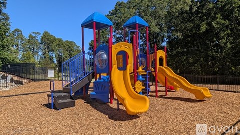 A playground with a yellow slide and blue and red structures.