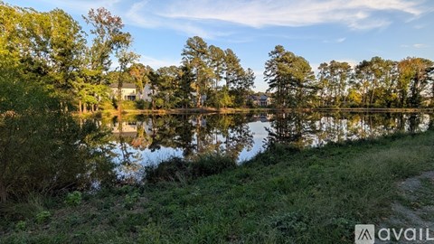 A serene landscape with a lake, trees, and a clear sky.