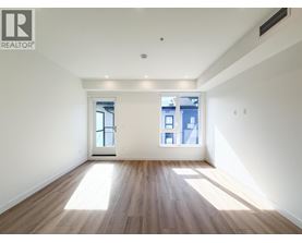 A spacious room with wooden floors and two windows.