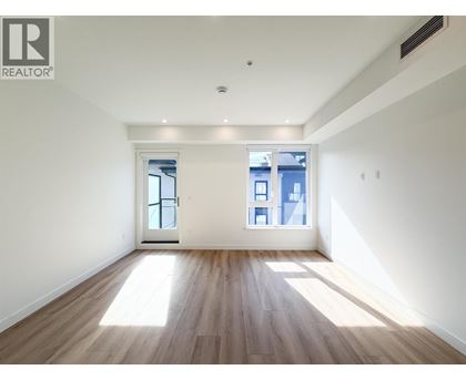 A spacious room with wooden floors and two windows.