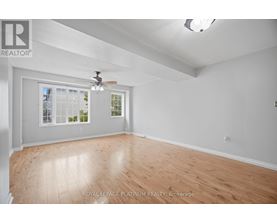 A room with a ceiling fan and a window with a view of trees.