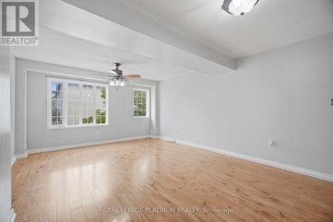 A room with a ceiling fan and a window with a view of trees.