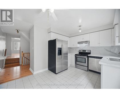 A kitchen with white cabinets and a black fridge.