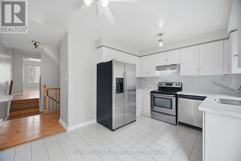 A kitchen with white cabinets and a black fridge.