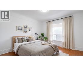 A bedroom with a large bed and a window with curtains.