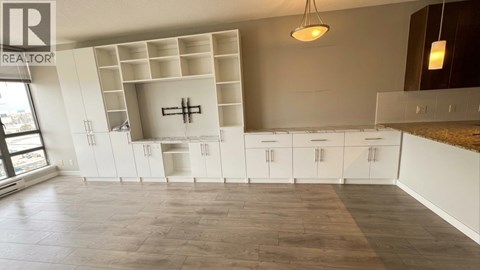 A realtor's image of a kitchen with white cabinets and a wooden floor.