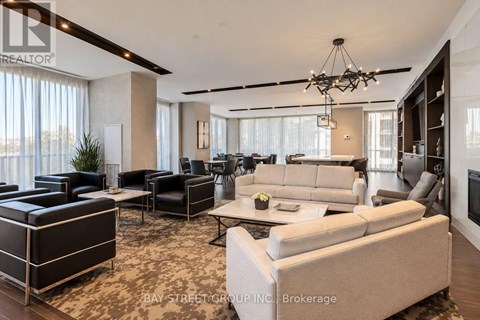 A spacious living room with a large couch and a chandelier.