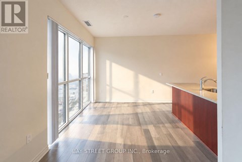 A spacious room with wooden flooring and a large window.