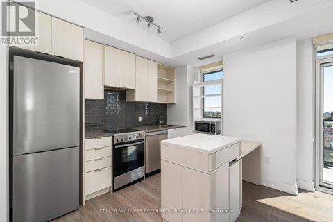 A modern kitchen with a refrigerator, oven, and microwave.