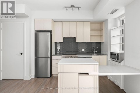 A modern kitchen with a refrigerator, microwave, and oven.