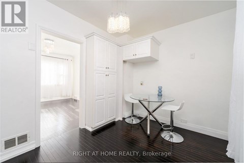 A dining room with a glass table and white chairs.