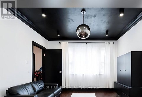 A black leather sofa sits in a room with a black ceiling and a chandelier hanging from it.