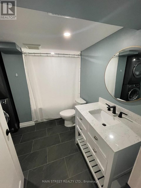 A bathroom with a toilet, sink, and mirror.
