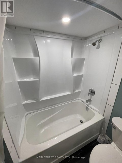 A white bathtub in a bathroom with a shower head.