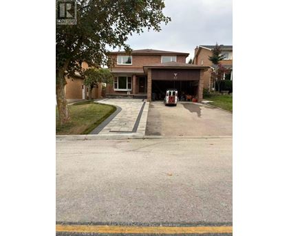 A house with a driveway and a tree in front of it.