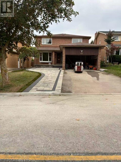 A house with a driveway and a tree in front of it.