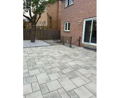 A patio with a grey tiled surface and a black fence.