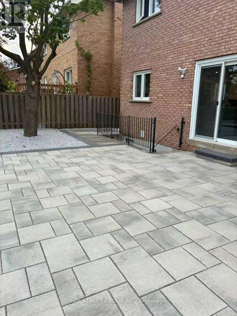 A patio with a grey tiled surface and a black fence.