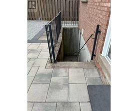 A manhole in a sidewalk with a metal railing.