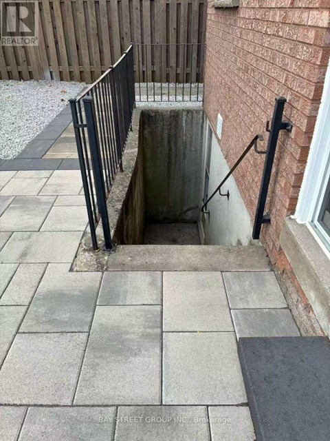 A manhole in a sidewalk with a metal railing.