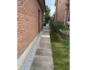 A brick wall with a concrete pathway in front of it.