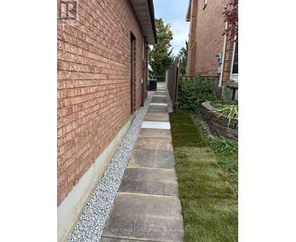A brick wall with a concrete pathway in front of it.