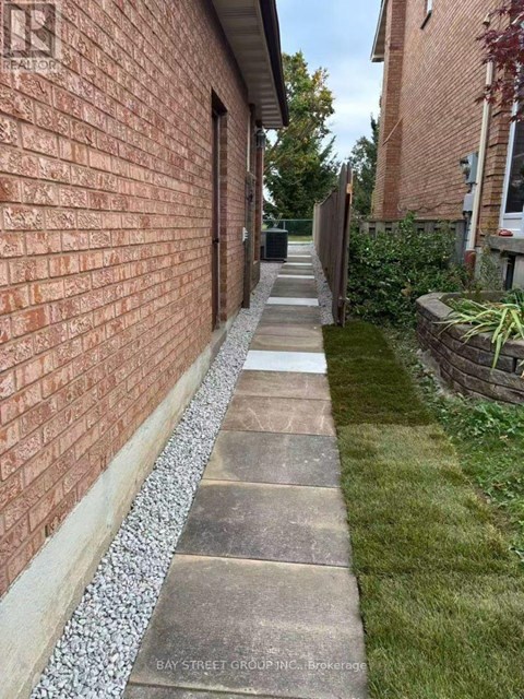 A brick wall with a concrete pathway in front of it.