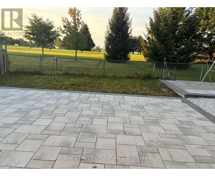 A paved walkway leads to a grassy area with a fence.