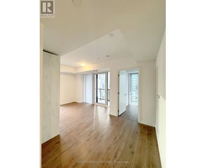 A spacious room with wooden floors and white walls.