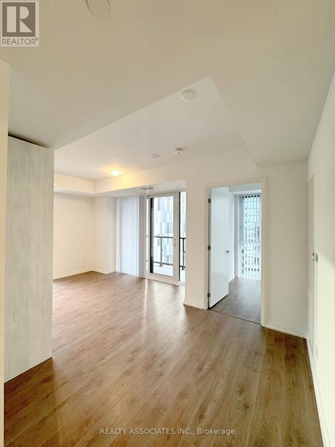 A spacious room with wooden floors and white walls.