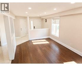 A spacious room with wooden flooring and white walls.