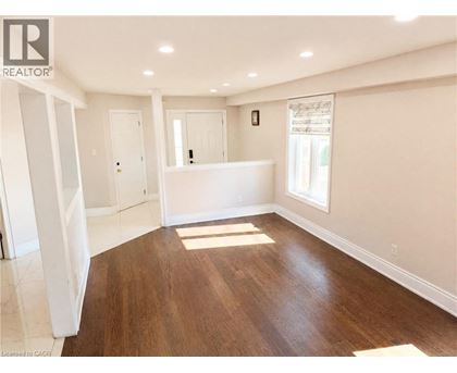 A spacious room with wooden flooring and white walls.