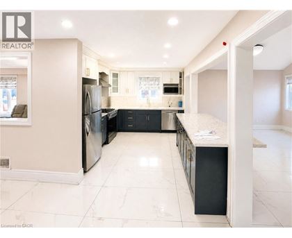 A spacious kitchen with a refrigerator, oven, and sink.