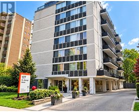 A tall apartment building with the number 177 on a sign in front of it.