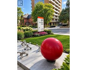 A red ball sculpture is in front of a building with a sign that says 177 St. George Street.