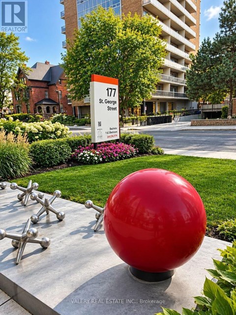 A red ball sculpture is in front of a building with a sign that says 177 St. George Street.
