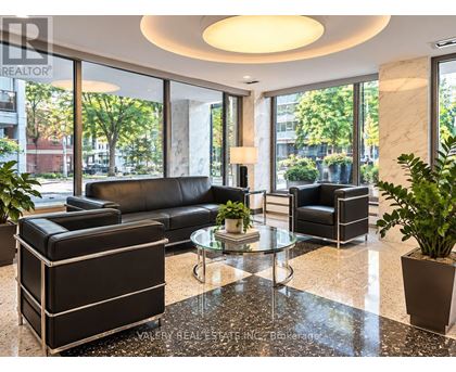 A living room with a black couch and a glass table.